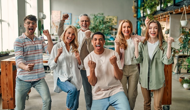 Pessoas criativas multirraciais em um escritório moderno. Grupo de jovens empresários e chefe sênior estão trabalhando juntos com laptop, tablet, smartphone, caderno, gráficos. Equipe de sucesso em coworking