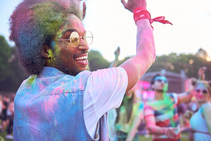 Foto pessoas dançando enquanto brincam com tinta em pó durante o festival contra o céu