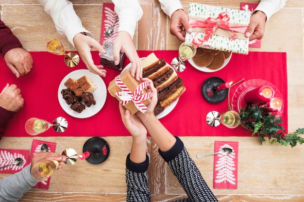 Pessoas dando caixas de presente de natal para o outro na mesa festiva