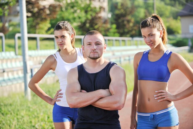 Pessoas de atletismo em grupo em pé e posando no início da manhã no estádio com pista de corrida atlética