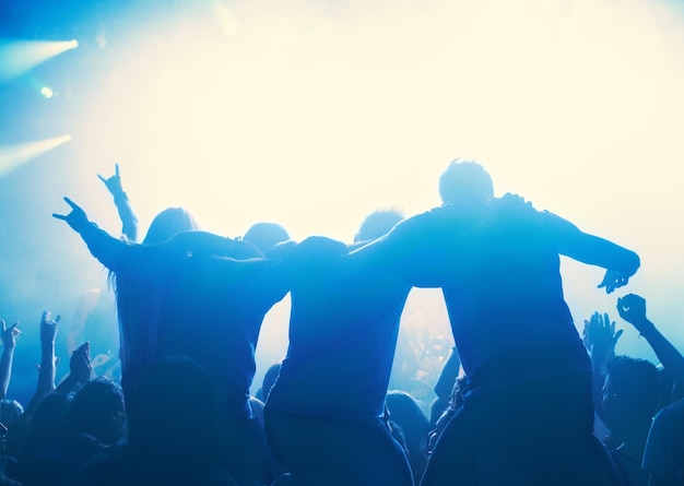 Foto pessoas de boate e público com silhueta ou luzes para concerto de festa ou festival de rave com dança e dj disco evento psicodélico e performance com multidão de entretenimento e gesto de mão