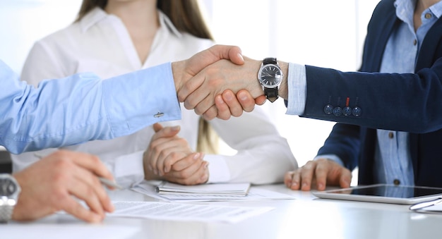 Pessoas de negócios apertando as mãos na reunião ou negociação, close-up. Grupo de empresários e mulheres desconhecidos no escritório moderno. Trabalho em equipe, parceria e conceito de aperto de mão, imagem tonificada