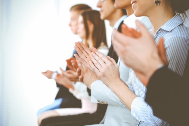 Pessoas de negócios batendo palmas e aplausos em reunião ou conferência, close-up de mãos. Grupo de empresários e mulheres desconhecidos no escritório branco moderno. Trabalho em equipe de sucesso ou conceito de coaching corporativo.