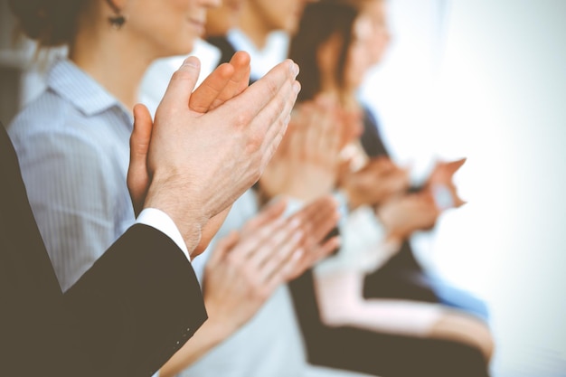 Pessoas de negócios batendo palmas e aplausos em reunião ou conferência, close-up de mãos. Grupo de empresários e mulheres desconhecidos no escritório branco moderno. Trabalho em equipe de sucesso ou conceito de coaching corporativo.