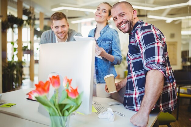 Foto pessoas de negócios em pé na mesa no escritório criativo a sorrir