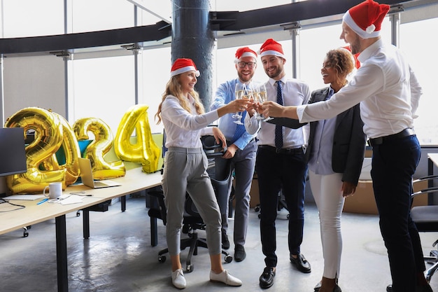 Foto pessoas de negócios estão a celebrar o feliz natal num escritório moderno e a beber champanhe.