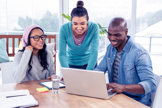 Pessoas de negócios feliz olhando para laptop no escritório criativo