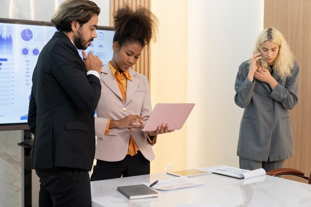 Foto pessoas de negócios inteligentes e diversas trabalhando juntas em uma reunião de negócios a equipe de gerentes executivos analisa dados de marketing usando laptop enquanto a mulher de negócios liga para o investidor conferência ornamentada.