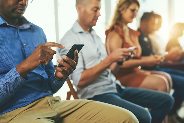 Pessoas de negócios modernos casuais enviando mensagens de texto em aplicativos de rede de mídia social em seus telefones celulares digitais grupo de profissionais enviando mensagens de texto em seus celulares juntos em uma fileira