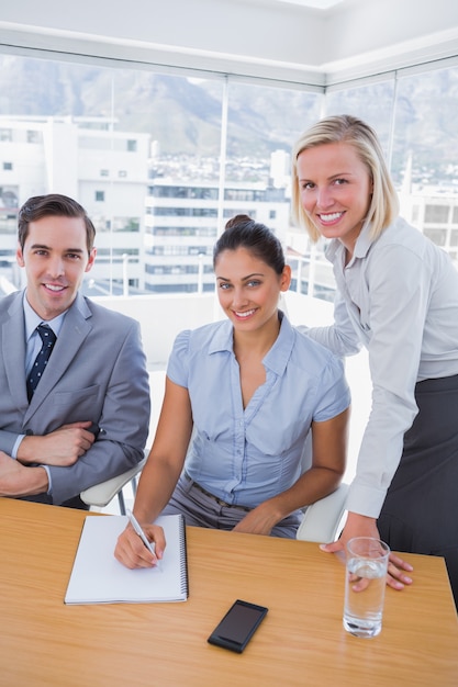 Foto pessoas de negócios na mesa com bloco de notas sorrindo para a câmera