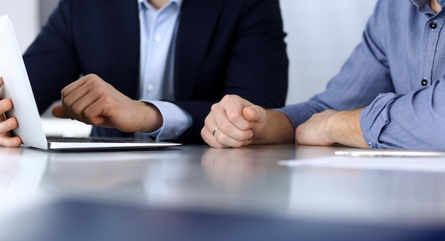 Pessoas de negócios usando laptop enquanto trabalham juntos na mesa do escritório moderno