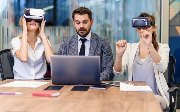 Foto pessoas de negócios usando óculos de realidade virtual durante a reunião. equipe de desenvolvedores testando o fone de ouvido de realidade virtual e discutindo novas idéias para melhorar a experiência visual.