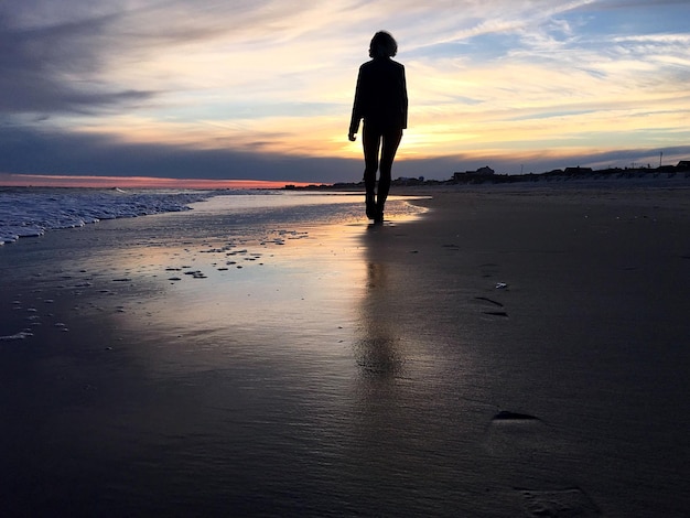 Foto pessoas de pé na praia ao pôr-do-sol