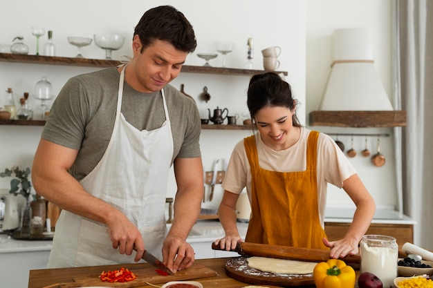 Foto pessoas de tiro médio cozinhando pizza juntas