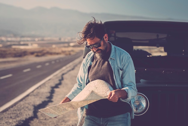 Pessoas de viagem e aventura com estilo de vida do conceito de veículo Um homem do lado de fora do carro off road e lendo um mapa de papel para encontrar as estradas e o destino Viagem e viagem turística perdida