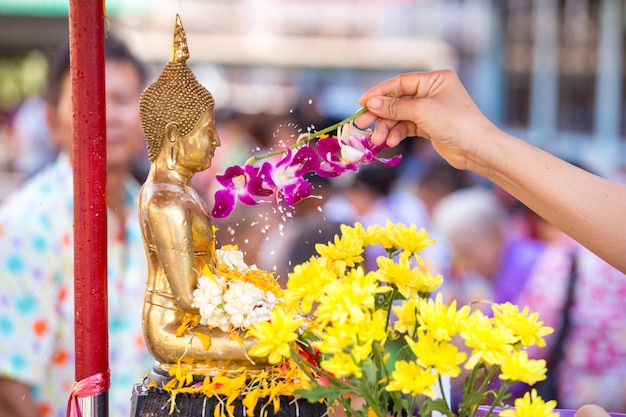 Pessoas derramando água a estátua budista e dá a bênção na Tailândia Songkran festival anual no templo budista