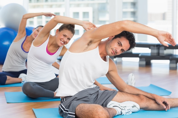 Pessoas desportivas que se estendem na aula de ioga