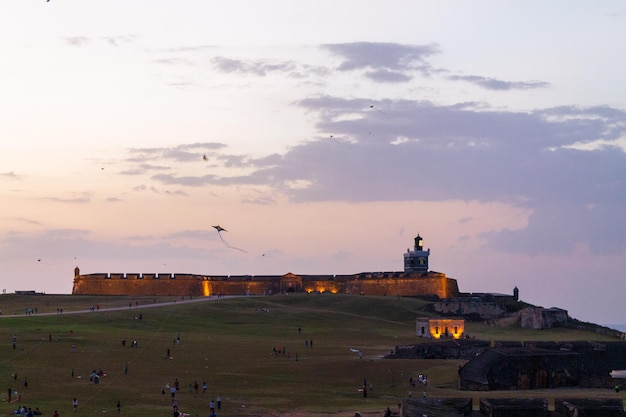 Pessoas e crianças estão empinando pipas ao pôr do sol