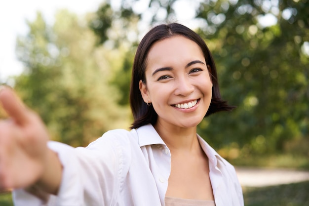 Pessoas e estilo de vida feliz mulher asiática tira selfie na foto do parque no smartphone sorrindo e olhando