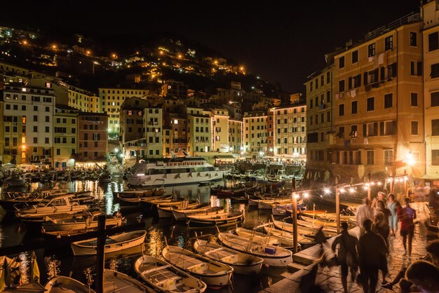 Pessoas em barcos na calçada em camogli à noite