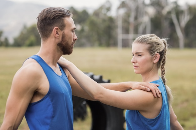 Pessoas em forma fazendo exercícios de alongamento no campo de treinamento