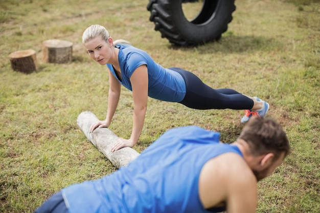 Pessoas em forma fazendo exercícios de flexão no campo de treinamento