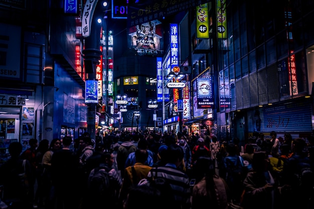 Pessoas em meio a edifícios com outdoors iluminados na cidade à noite
