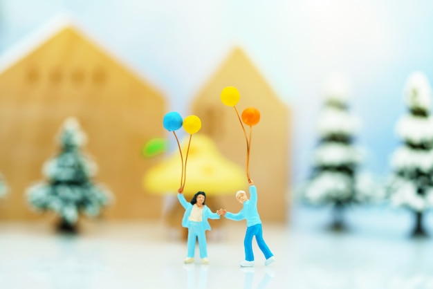 Pessoas em miniatura: as crianças gostam de balões coloridos antes da árvore de Natal.