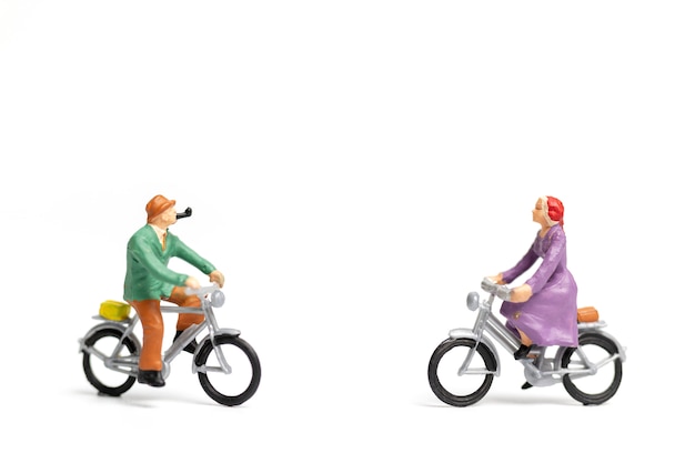 Pessoas em miniatura: casal andar de bicicleta no fundo branco