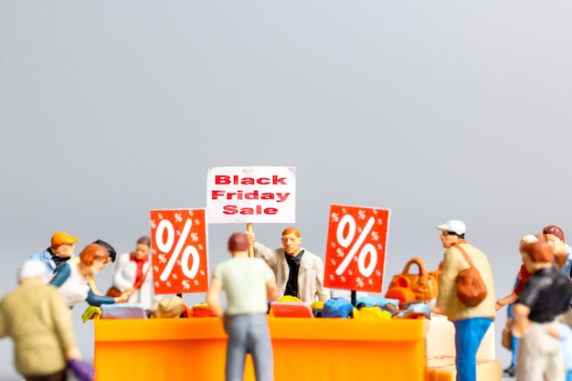 Pessoas em miniatura, compradores com bandeja de descontos para comprar itens com desconto, conceito Black friday