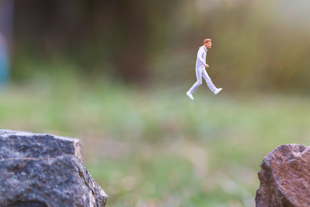 Pessoas em miniatura: correndo na falésia da rocha com fundo de natureza