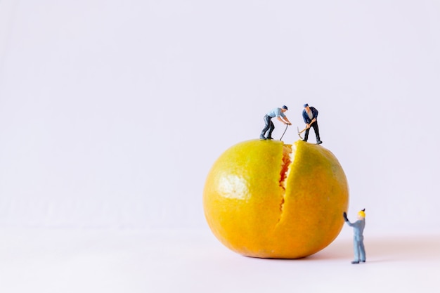 Pessoas em miniatura: equipe de trabalho trabalhando em cima de um fundo laranja