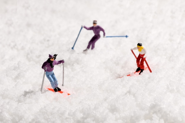 Pessoas em miniatura esquiando na neve fresca do inverno