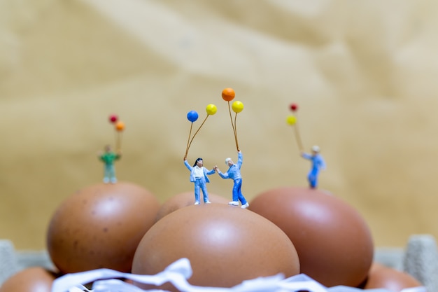 Pessoas em miniatura: família feliz segurando balão comemorando ovos de páscoa