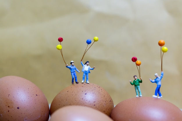 Pessoas em miniatura: família feliz segurando balão comemorando ovos de Páscoa