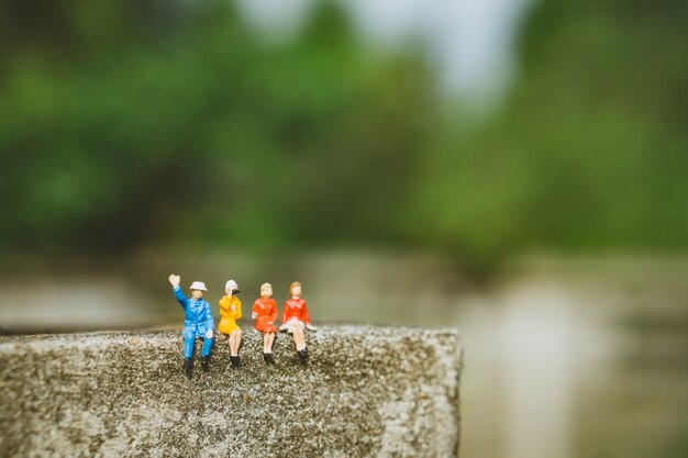 Pessoas em miniatura - grupo de pessoas sentadas na parede