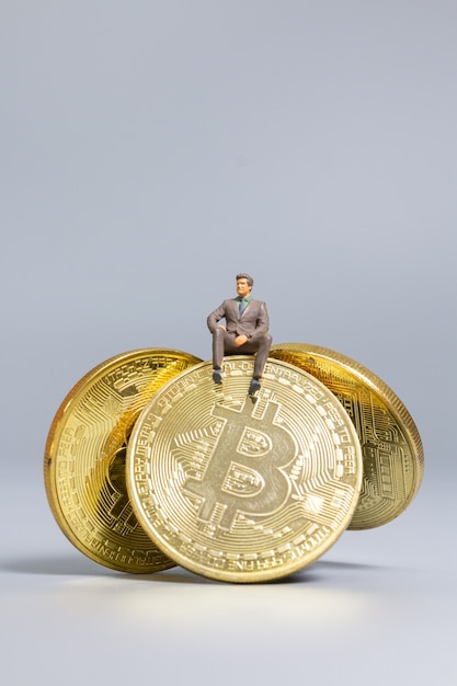 Pessoas em miniatura homem de negócios sentado sobre moedas bitcoin