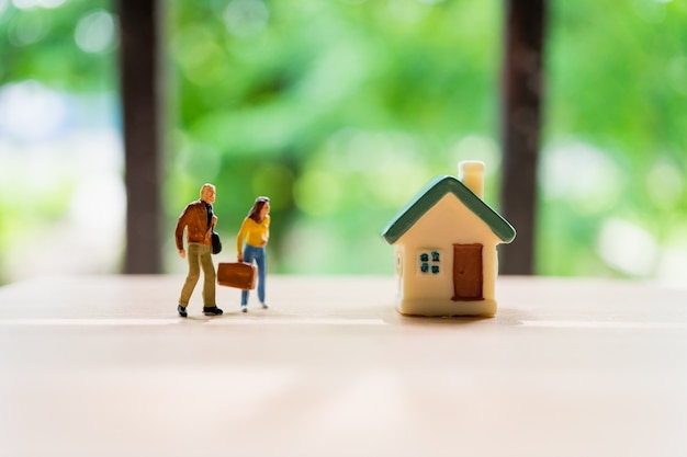 Pessoas em miniatura, homem e sua esposa em frente a casa no uso de fundo verde natureza para fam