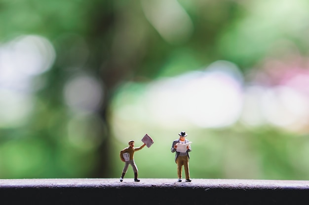 Pessoas em miniatura, homem lendo jornal usando como conceito de negócio