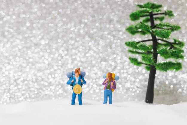 Pessoas em miniatura, mochileiros andando na neve