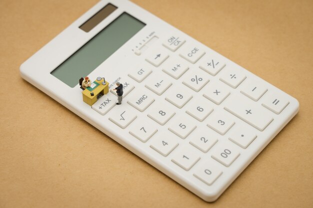 Pessoas em miniatura Pague fila Renda anual (IMPOSTO) para o ano na calculadora.