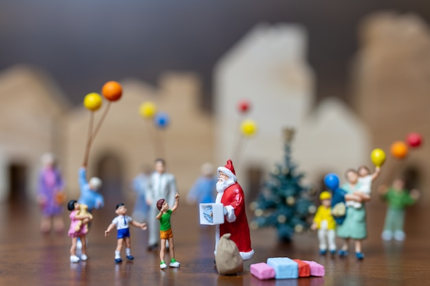 Pessoas em miniatura: Papai Noel e família feliz