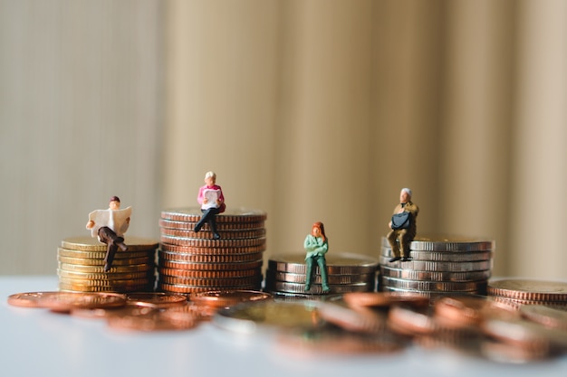 Pessoas em miniatura, sentado em moedas de pilha usando como negócios, finanças e conceito social