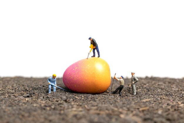 Pessoas em miniatura trabalham em ovos de Páscoa para o dia de Páscoa