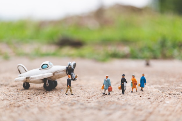 Pessoas em miniatura: viajantes segurando bagagem de mão entrar no avião