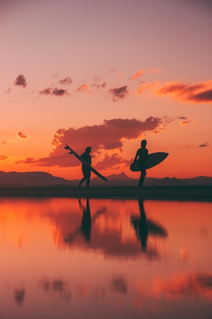 Foto pessoas em silhueta de pé na costa contra o céu laranja