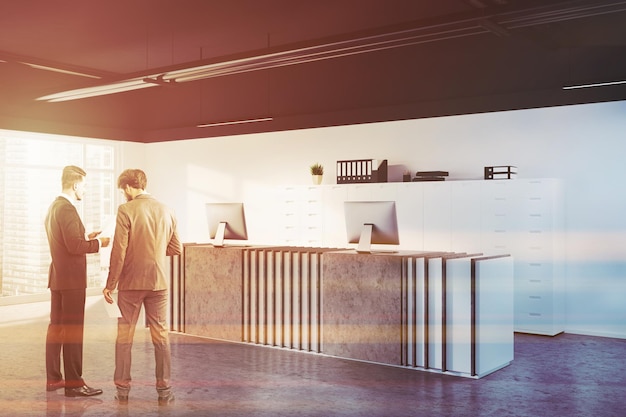 Pessoas em um canto de escritório com paredes brancas, piso de concreto e uma elegante mesa de recepção no saguão. Empresa internacional e conceito de negócio global. imagem tonificada simulada de renderização 3D