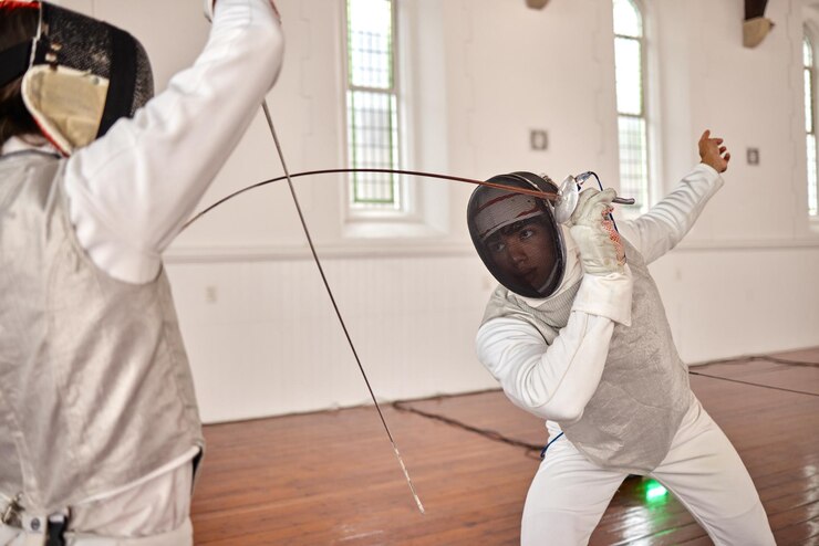 Foto pessoas esgrimindo e treinando para uma luta de espadas e exercícios com uma arma ou duelo lutando em esportes com atleta de artes marciais combate em equipe e competição com lâmina e equipamento de caça