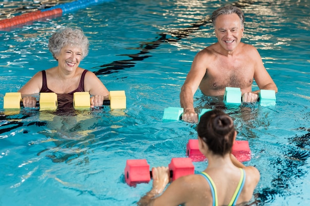 Pessoas fazendo exercícios com halteres aquáticos em uma piscina