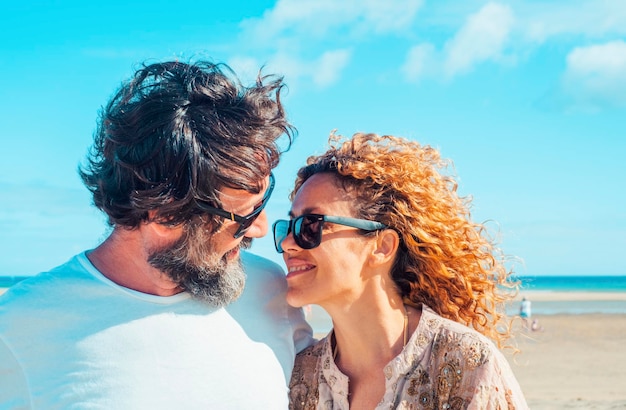 Pessoas felizes aproveitando as férias de verão na praia Homem e mulher sorrindo e olhando um para o outro em local tropical Conceito de viagem e casal alegre com céu azul no fundo